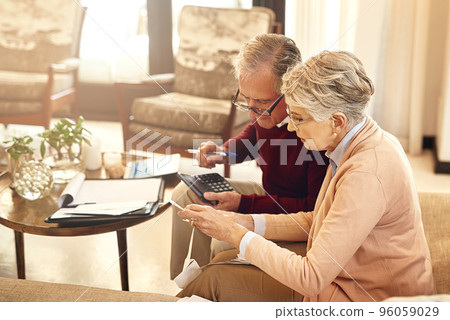 Making sure all our debts are in order. Shot of an elderly couple working out a budget while sitting on the living room sofa. Making sure all our debts are in order. Shot of an elderly couple working out a budget while sitting on the living room sofa. 96059029