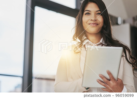 Shes a business visionary. Shot of a young businesswoman working on a digital table in an office. Shes a business visionary. Shot of a young businesswoman working on a digital table in an office. 96059099