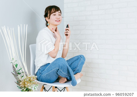 Asian woman doing neck care while sitting in a chair (neck) 96059207