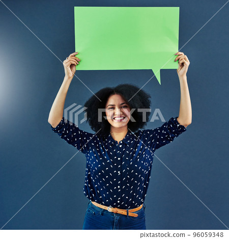 Lets start a dialogue. Studio shot of a young woman holding up a blank speech bubble against a blue background. Lets start a dialogue. Studio shot of a young woman holding up a blank speech bubble against a blue background. 96059348