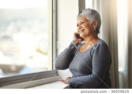 One hello can make someones day. Shot of a mature woman using her cellphone at home. One hello can make someones day. Shot of a mature woman using her cellphone at home. 96059629