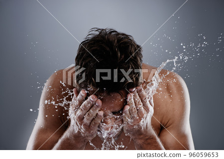 Getting clean. Studio shot of a man washing his face. 96059653