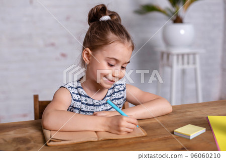 Inspired little girl at the table draw with crayons or do home work Inspired little girl at the table draw with crayons or do home work 96060210