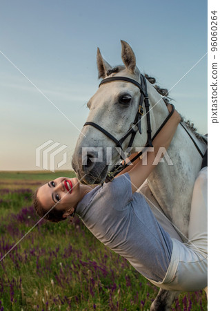 Beautiful young girl smile at her horse dressing uniform competition: outdoors portrait on sunset Beautiful young girl smile at her horse dressing uniform competition: outdoors portrait on sunset 96060264