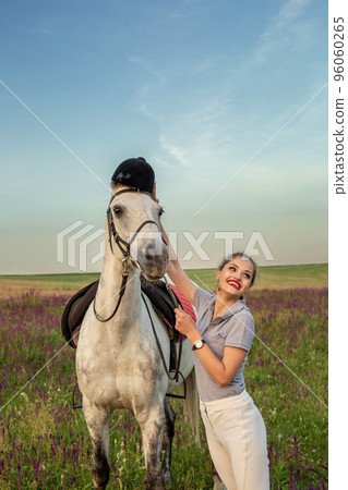 Beautiful young girl smile at her horse dressing uniform competition: outdoors portrait on sunset 96060265