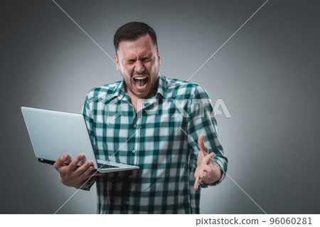 Portrait of young handsome man using laptop, wearing plaid shirt 96060281