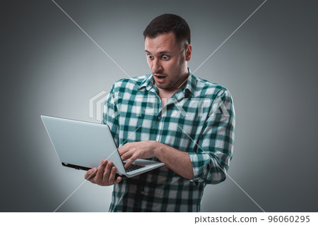 Businessman holding a laptop on gray background. Businessman holding a laptop on gray background. 96060295
