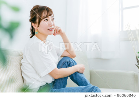 一位微笑的日本女性在家裡放鬆和在沙發上放鬆時感到快樂的簡介 96060840