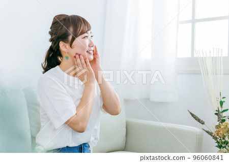 日本女性坐在沙發上用化妝品保濕 96060841