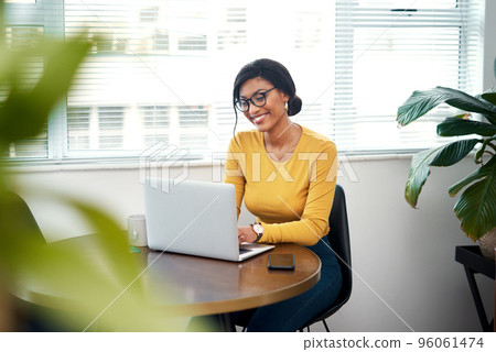 Working from home makes me happy. Cropped shot of an attractive young woman sitting alone in her home and using her laptop. 96061474