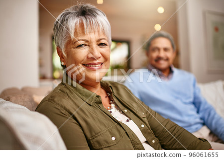 We did good. Portrait of a happy older woman relaxing on the sofa with her husband in the background. 96061655