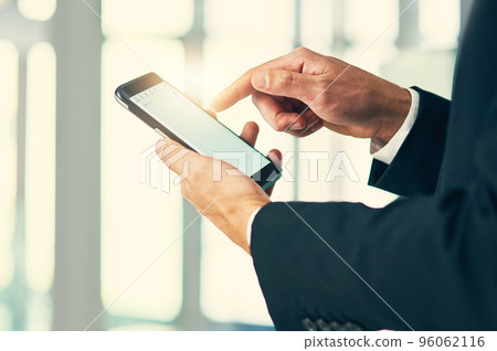 Engaging with clients in mobile form. Cropped shot of corporate businessmen texting on a cellphone. 96062116