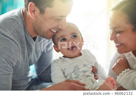 Born into a home full of love. Shot of an adorable baby boy bonding with his father and father at home. 96062132