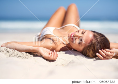 Lifes a beach. Shot of an attractive young woman lying on the beach in a bikini. 96062188