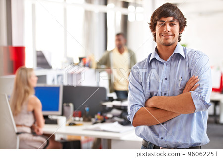Positivity and confidence make him a great team player. Shot of a handsome young businessman with his colleagues blurred in the background. 96062251