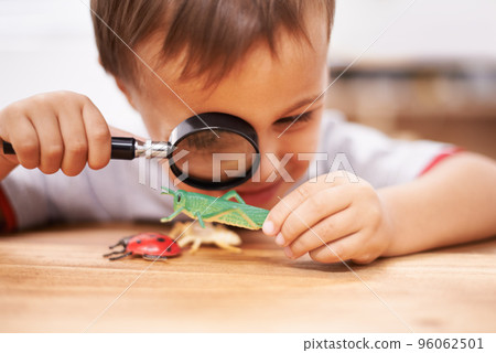Inspecting some curious creatures. Shot of a young boy inspecting his toys with a magnifying glass. Inspecting some curious creatures. Shot of a young boy inspecting his toys with a magnifying glass. 96062501