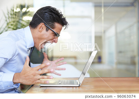 When your computer crashes. Profile of an angry businessman shouting at his laptop at work. When your computer crashes. Profile of an angry businessman shouting at his laptop at work. 96063074