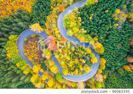 Winding forest asphalt road on colorful autumn day. Serpentine in natural landscape. Aerial view from drone. 96063345