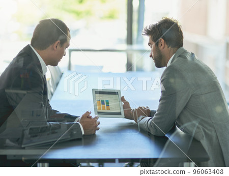 Analyzing the companys numbers. Shot of two colleagues looking at a graph on a digital tablet together in an office. Analyzing the companys numbers. Shot of two colleagues looking at a graph on a digital tablet together in an office. 96063408
