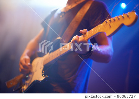 Hitting the right notes. A guitarist playing his heart out beneath the strobe lights. 96063727