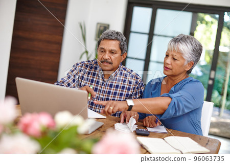Budgeting with the help from technology. Shot of a senior couple working on their budget together at home. Budgeting with the help from technology. Shot of a senior couple working on their budget together at home. 96063735