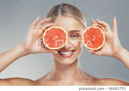 Grapefruit, skincare and face of a woman with smile for health, wellness and healthcare with food against a grey studio background. Nutrition, happiness and model with fruit for body detox and diet Grapefruit, skincare and face of a woman with smile for health, wellness and healthcare with food against a grey studio background. Nutrition, happiness and model with fruit for body detox and diet 96063755
