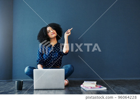 Act on your dreams. Studio shot of an attractive young woman looking thoughtful while using a laptop against a blue background. 96064228