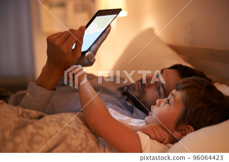 Modern bedtime story. A father reading a bedtime story to his son from an e-reader. 96064423