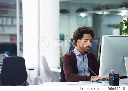 Putting in the hours to get work done. Shot of a young businessman sitting at a desk. 96064648