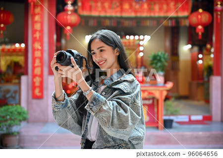 Pretty Asian woman taking a photo with camera during her vacation at tradition asian temple. Pretty Asian woman taking a photo with camera during her vacation at tradition asian temple. 96064656