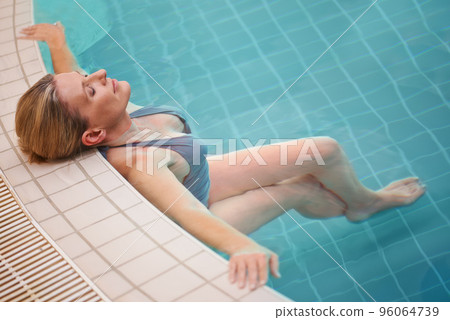 Feeling at one with the water. Cropped shot of a mature woman relaxing in an indoor swimming pool. Feeling at one with the water. Cropped shot of a mature woman relaxing in an indoor swimming pool. 96064739