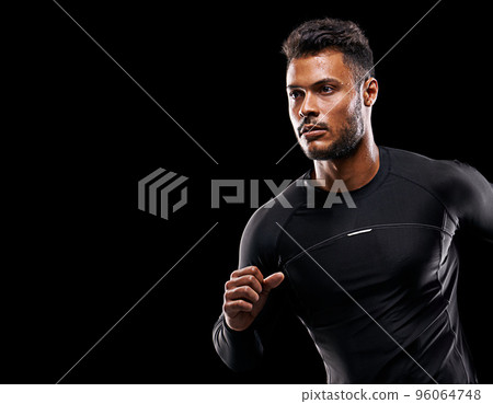 Always give 100 percent. Studio shot of a handsome young man running against a black background. 96064748