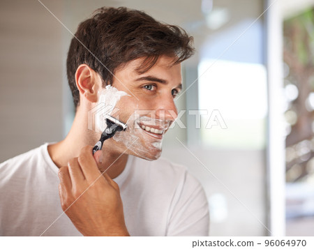 Enjoying his morning routine. Cropped shot of a young man shaving his facial hair with a disposable blade. 96064970