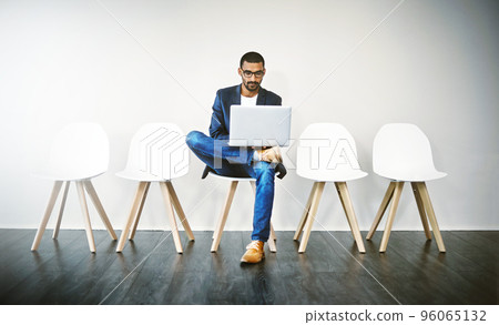 Familiarizing myself with the ins and outs of the company. Shot of a young businessman using a laptop while waiting in line. 96065132