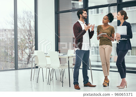 Clarifying his ideas to the team. Shot of a group of colleagues having a discussion in an office. Clarifying his ideas to the team. Shot of a group of colleagues having a discussion in an office. 96065371