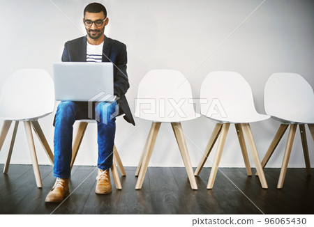 Preparing an interesting introduction before his interview. Shot of a young businessman using a laptop while waiting in line. 96065430