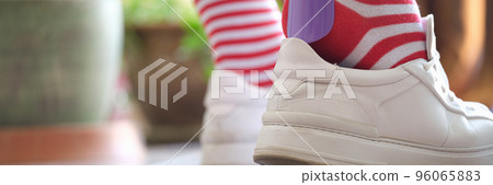 Person puts shoes white sneakers using shoehorn Person puts shoes white sneakers using shoehorn 96065883