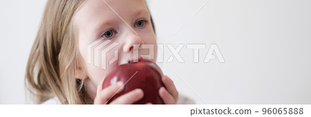 Little girl eating heartily fresh red apple 96065888