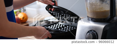 Woman preparing belgian waffle maker in kitchen 96066012