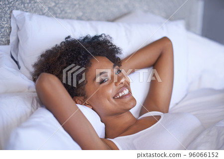 Waking up nice and slowly on a weekend. Cropped shot of a young woman lying on her back. 96066152