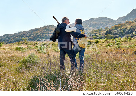 Rear view of a couple hugging while walking through a rural mead Rear view of a couple hugging while walking through a rural mead 96066426