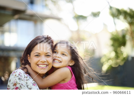 I love you mom. A cute little girl hugging her mom while they are standing in the garden. 96066611