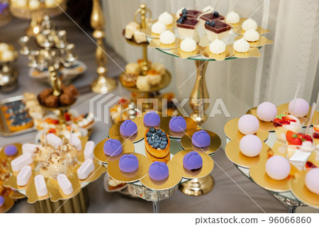 Table with cakes, sweets, candy, buffet. Dessert table for a party goodies for the wedding banquet area. Close up candy bar. Decorated delicious. 96066860