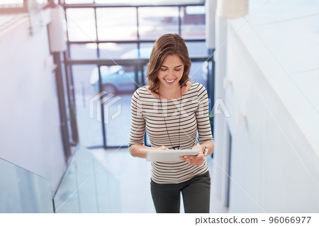 Places to be, people to meet...online. Shot of a young businesswoman using a digital tablet on the stairs in a modern office. 96066977