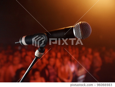Take the stage.... A microphone standing on a stage with a crowd in the background. Take the stage.... A microphone standing on a stage with a crowd in the background. 96066983