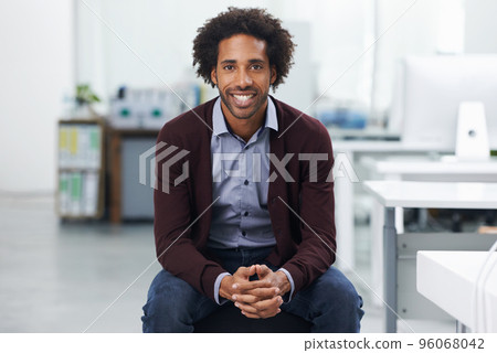 He knows its important to enjoy his work. Shot of a young businessman sitting in an office. He knows its important to enjoy his work. Shot of a young businessman sitting in an office. 96068042