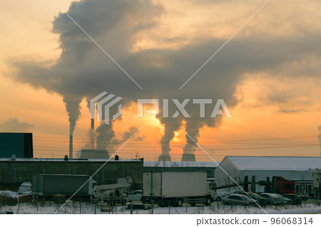 The smoke from the CHP chimneys blocked the sun in the evening sky at sunset. In the foreground is a parking lot with a white truck on it. The smoke from the CHP chimneys blocked the sun in the evening sky at sunset. In the foreground is a parking lot with a white truck on it. 96068314