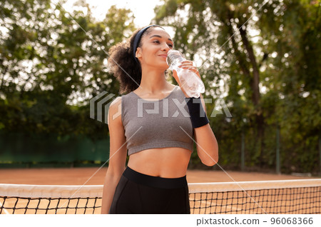 Pretty young girl drinking water after exercising 96068366