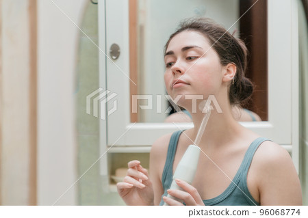 a young girl takes care of the skin of the face making procedures using the darsonval device while in the bathroom a young girl takes care of the skin of the face making procedures using the darsonval device while in the bathroom 96068774