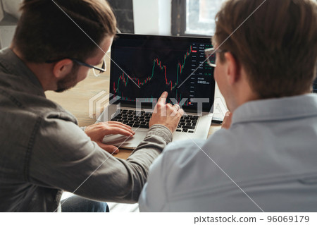 Over shoulder view of trader couch teaching another man basics of cryptocurrency investments Over shoulder view of trader couch teaching another man basics of cryptocurrency investments 96069179